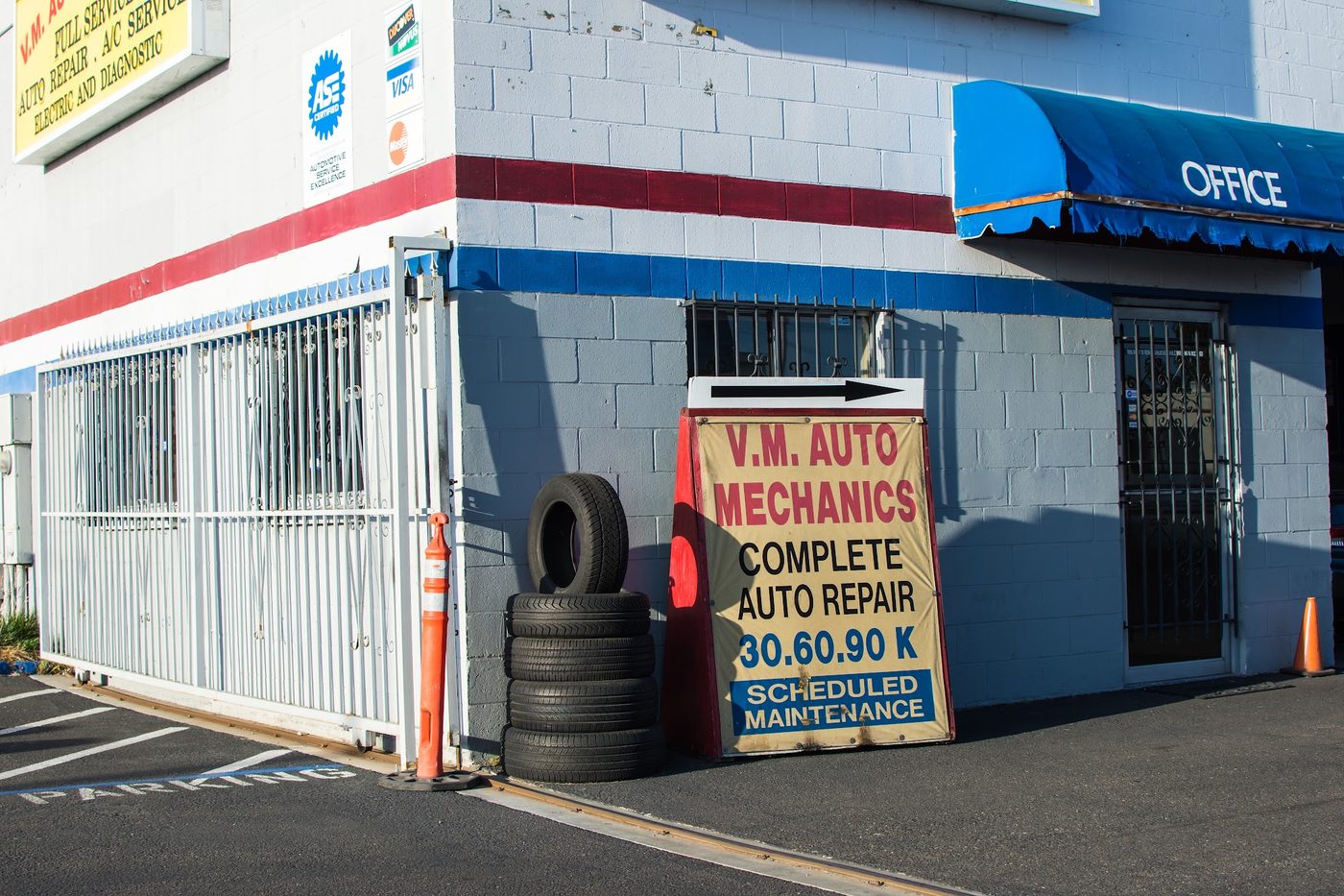 Office entrance with stacked tires and the 'Complete Auto Repair 30.60.90K Scheduled Maintenance' sign
